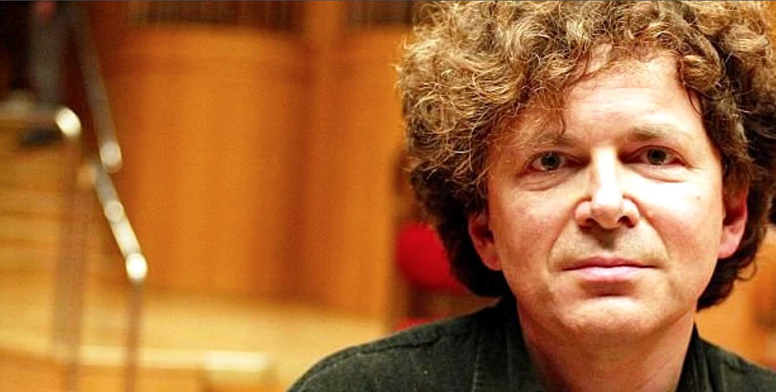 Portrait of a man with curly hair in a recording studio, highlighting music history and audio archival preservation.