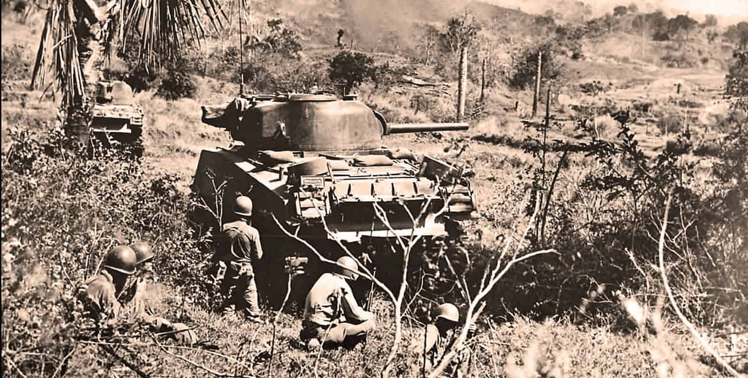 Vintage WWII tank being targeted by soldiers in a rural battlefield, highlighting historical military combat and wartime strategy photography.