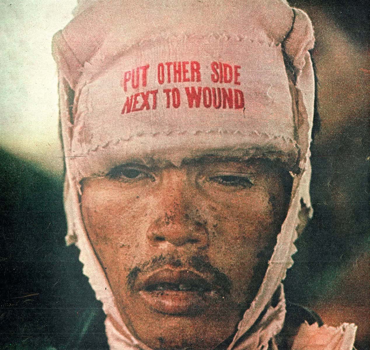 Wound care headgear with "Put Other Side Next to Wound" warning, associated with military or medical history, captured in vintage style.