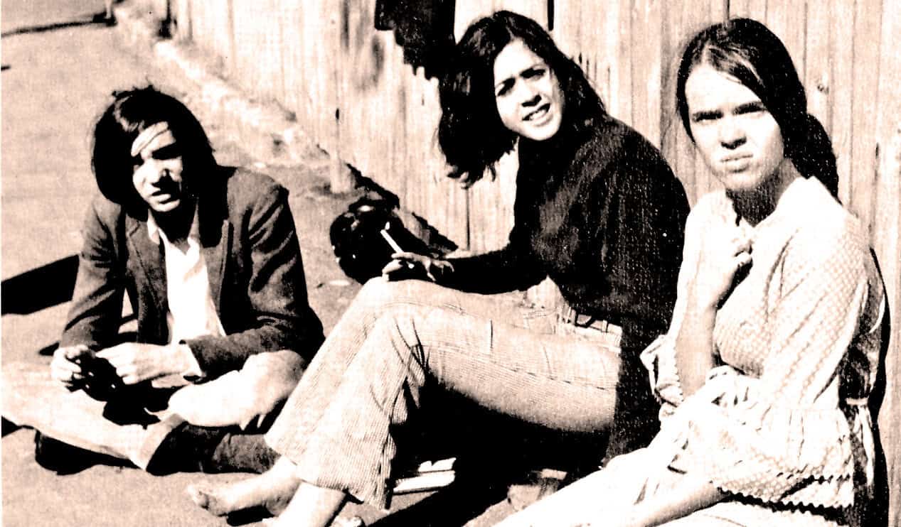 Teenage girls sitting outdoors, listening to music and talking, vintage black and white photo representing youth culture, 1960s.