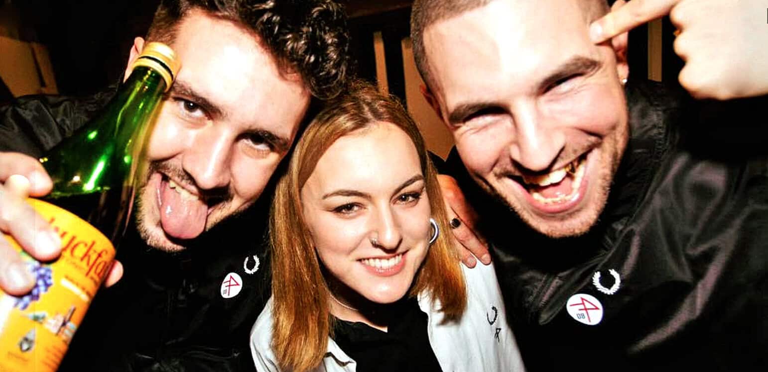 Happy young friends celebrating at a music event, showcasing lively social moments with music, laughter, and drink, emphasizing the vibrant atmosphere and youthful energy.