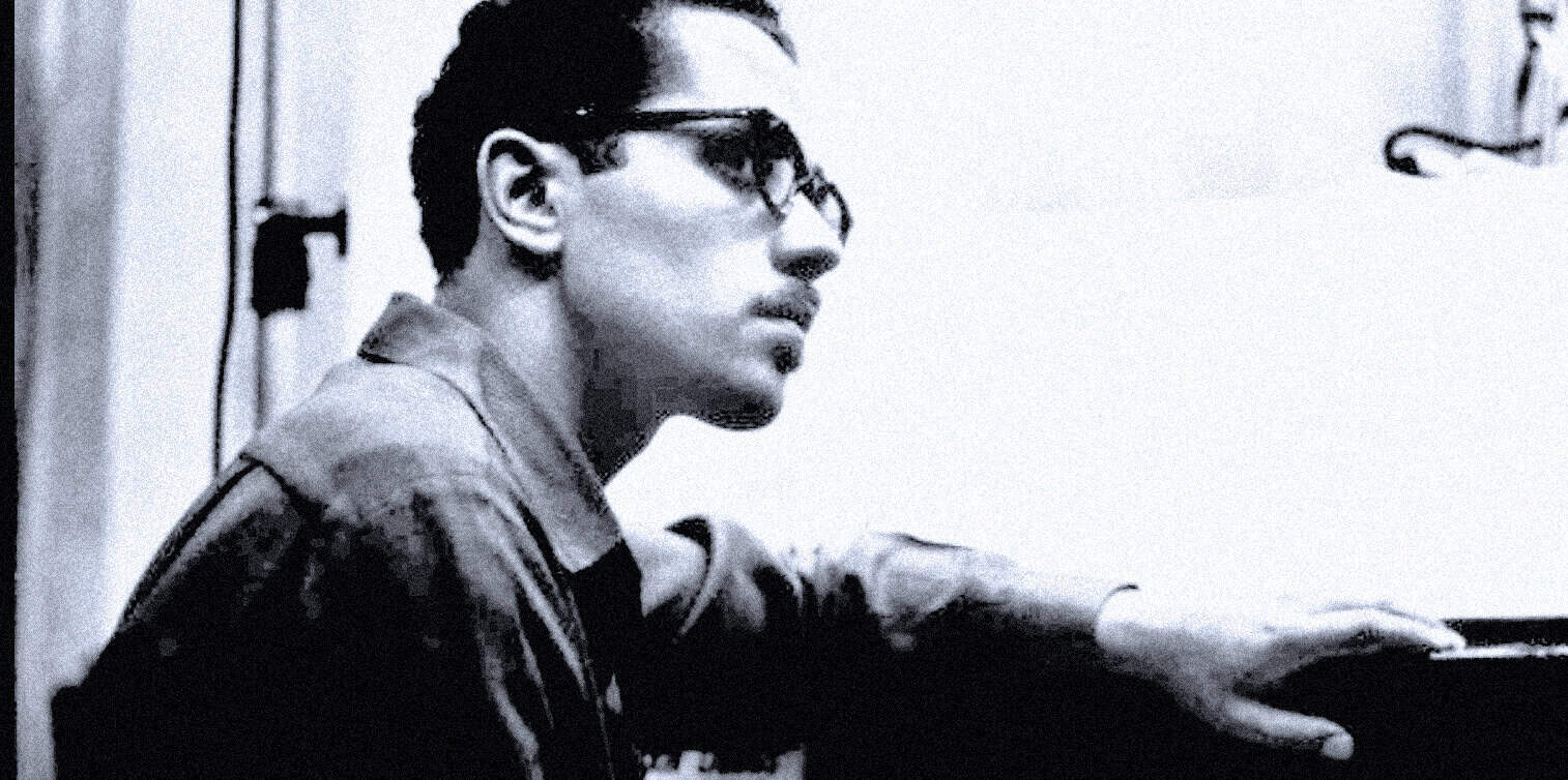 Young man playing piano with glasses, black and white photo, vintage music scene, nostalgic music archive, classic musician, historical music performance, timeless music memory.