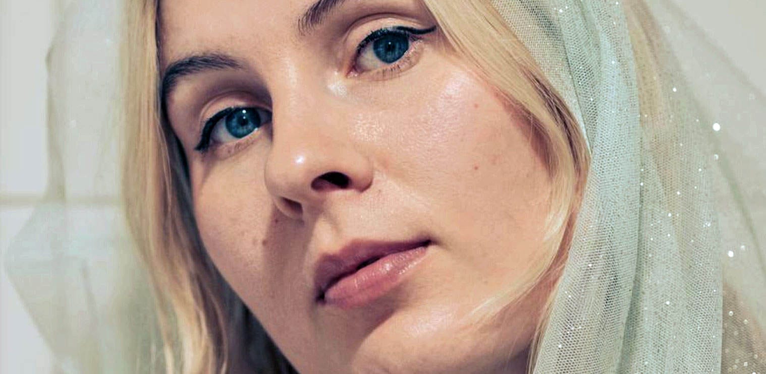 Close-up of a woman with blue eyes and blonde hair, wearing a sheer veil, representing news, history, and music archives for a sound archive website.