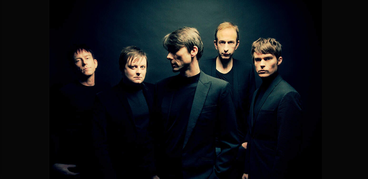 Leatherface band posing in dark studio background for music and band promotion, emphasizing alternative rock and music history.