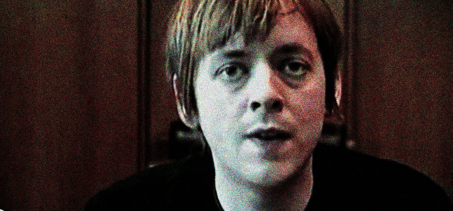 A woman with short, dark hair speaking in an interview or recording setting.