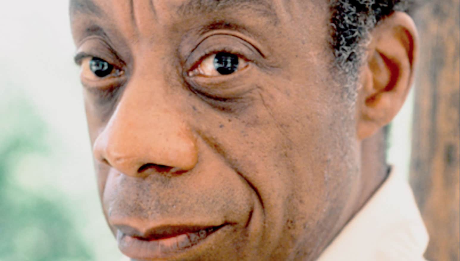 Close-up of an older African American man's face, highlighting expressive eyes and detailed skin texture, emphasizing history, news, and personal stories in a sound archive context.