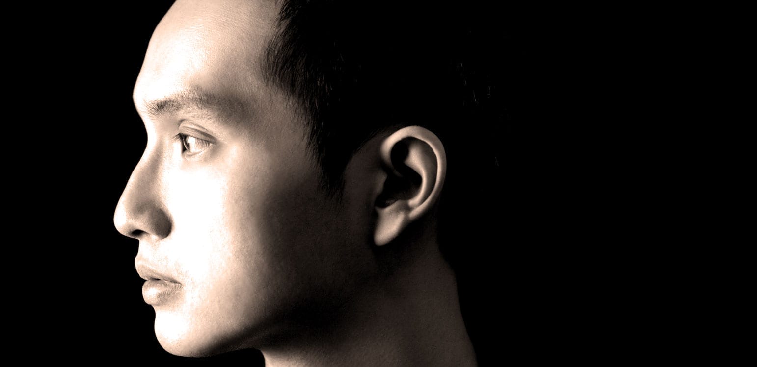 Young man's profile with short dark hair against a black background, emphasizing modern music, news, and history archive themes.