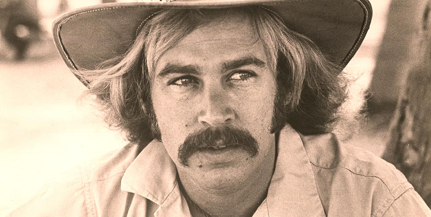 A sepia-toned photo of a man with a cowboy hat, mustache, and long hair, capturing a vintage western or music scene, related to historical sound archives, news, and music history.