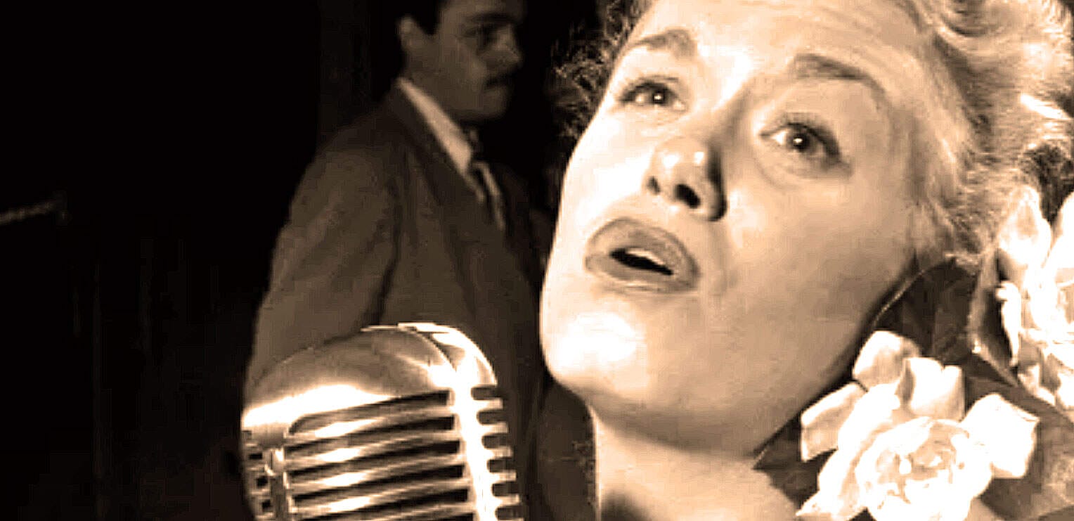 Vintage woman singing into a classic microphone in a music recording studio, with a man in the background, capturing an iconic historical scene of music and radio broadcasting, related to pastdaily.com.