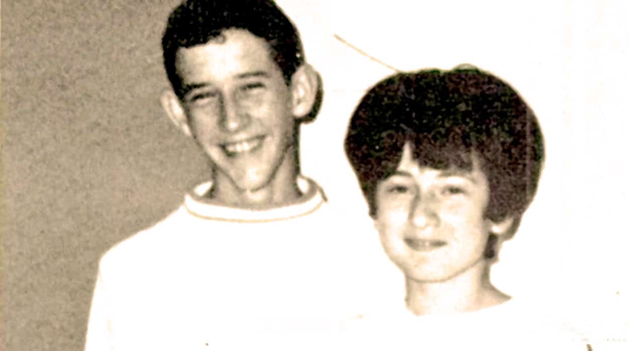 Smiling teenage boy and girl in vintage black-and-white photo, representing historical youth culture and memories.