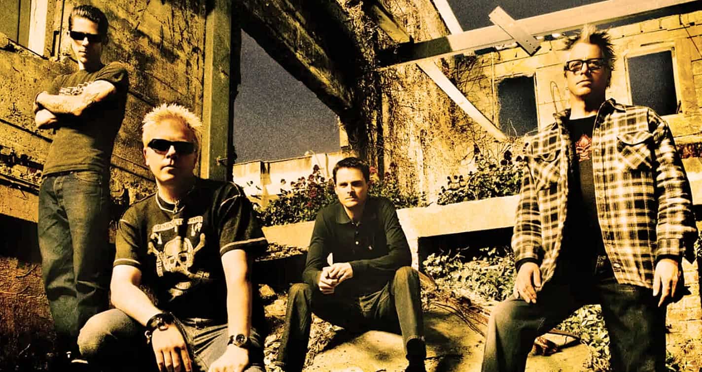 Teen band members posing outdoors in an urban, rustic setting for a music photo shoot, capturing the essence of rock music and youth culture.