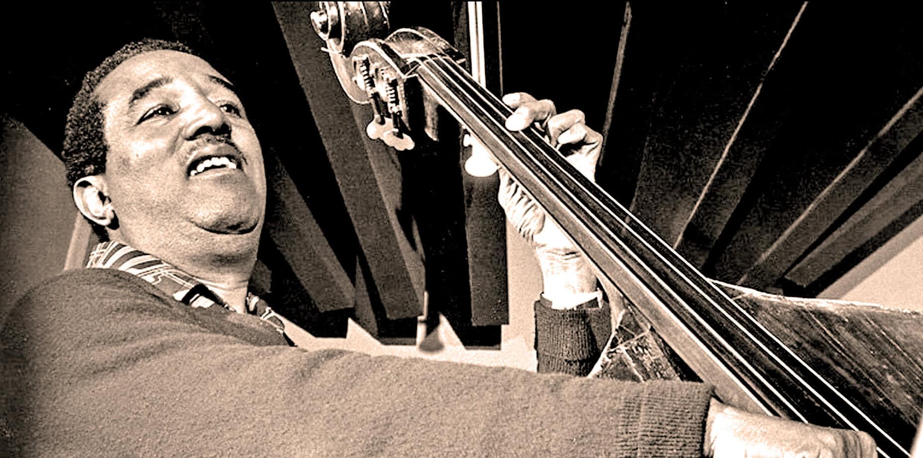 Vintage black and white photo of a jazz musician playing the double bass, capturing the essence of historical music archives, jazz history, and sound recordings.