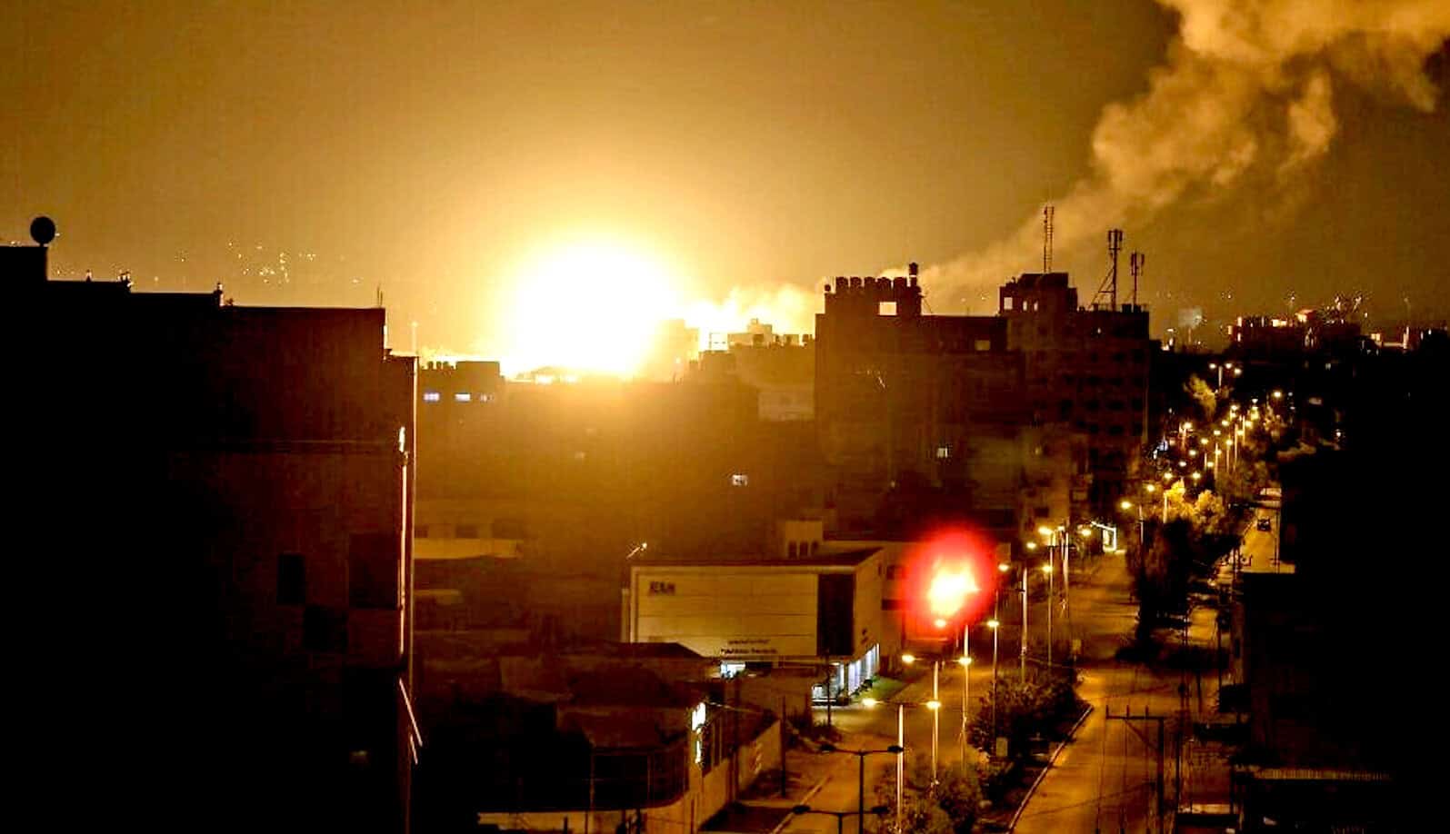 Explosion in an urban area during night with smoke and bright flames, city lights visible; related to news and history coverage of significant events.