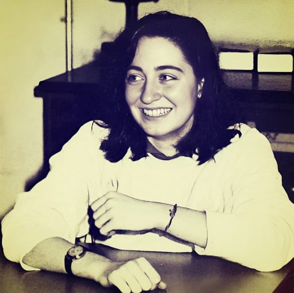 Girl smiling at desk in vintage setting, black and white photo.
