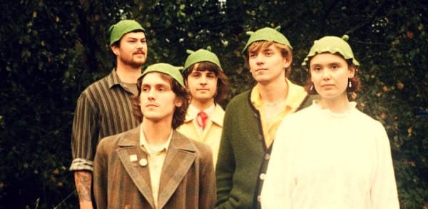 Vintage band members wearing green hats outdoors, showcasing classic music era style and retro fashion.