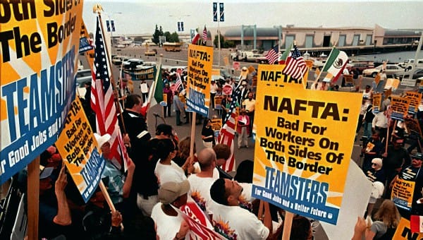 Protesters holding NAFTA signs and American flags at a labor rally advocating for workers' rights and border issues, reflecting historical and social activism during a public demonstration.