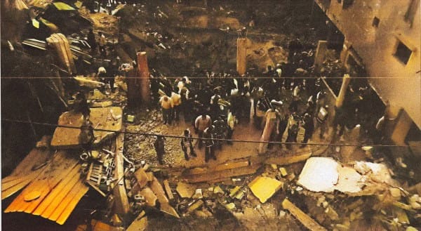 Collapsed building site with rescue workers and debris, illustrating a disaster response scene.