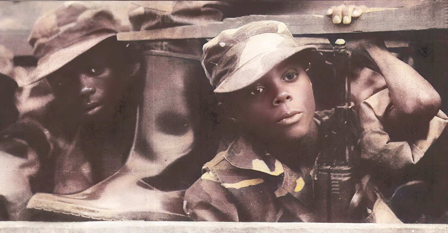 Children in military uniforms and helmets peering through a trench opening, evoking themes of war, youth, and resilience. Vintage black-and-white photograph highlighting historical military life and childhood amidst conflict.