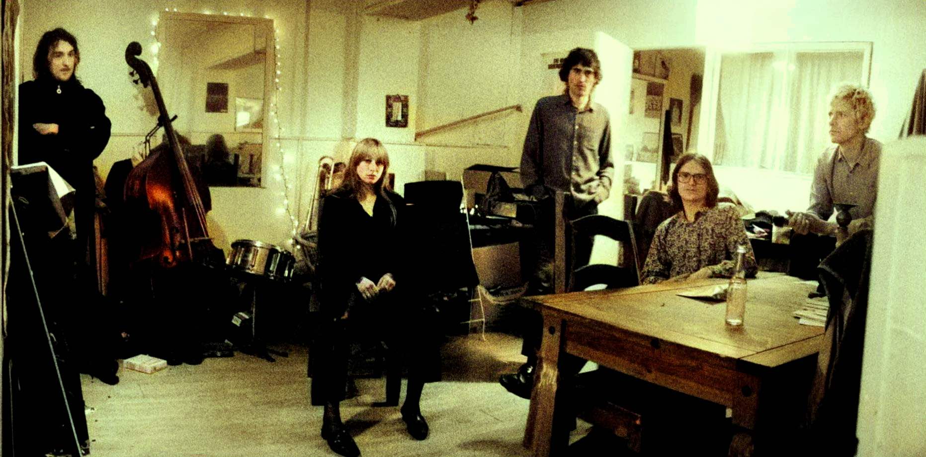 Vintage music band rehearsal in intimate recording studio, featuring instruments like upright bass, drums, and keyboard, capturing a nostalgic musical atmosphere at Past Daily archives.