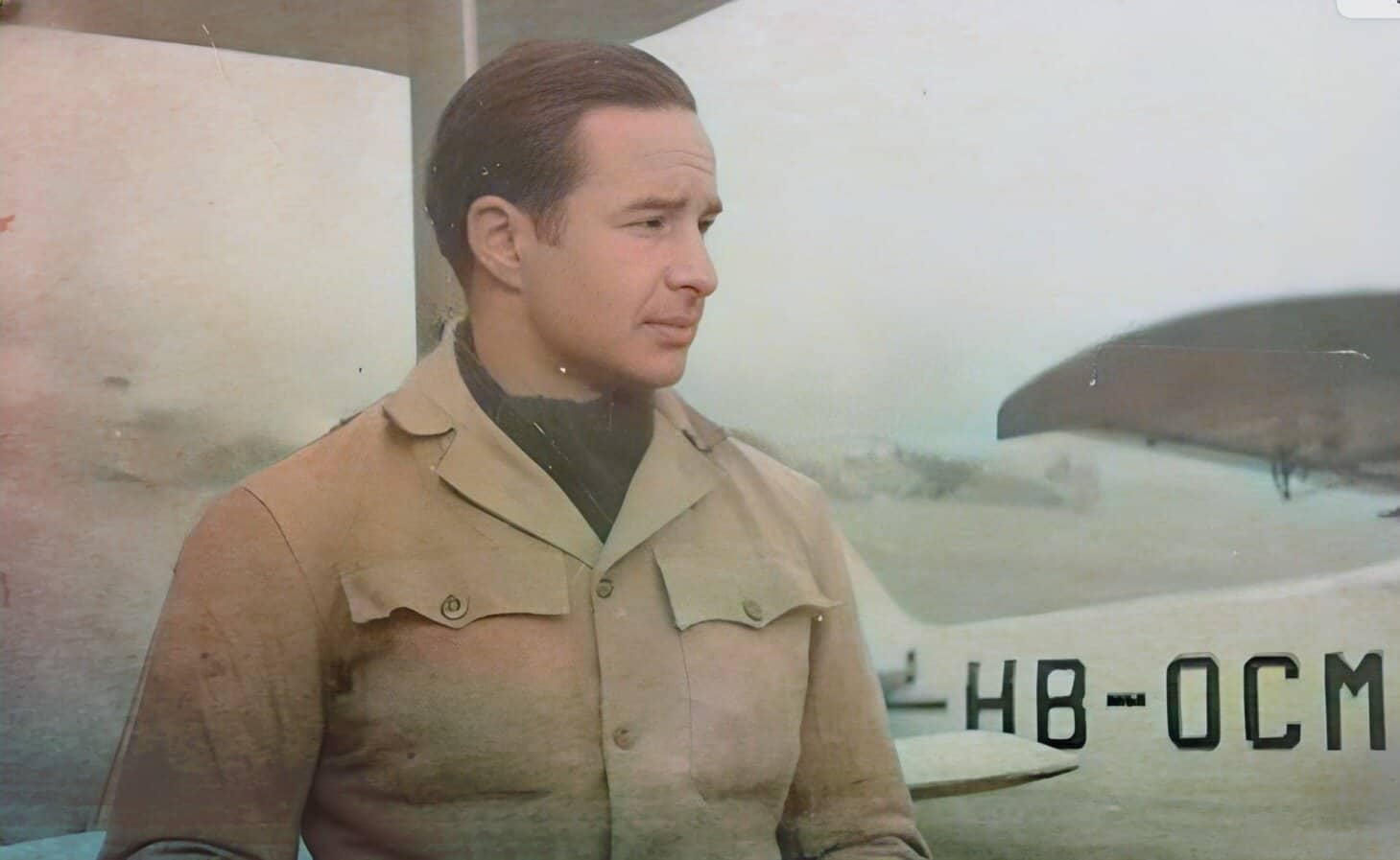 An image of a man in a beige military uniform standing in front of a fighter jet; vintage military aircraft, world history, war memorabilia, 20th-century aviation.