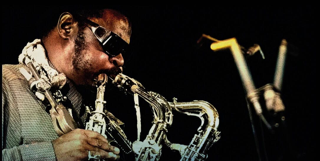 Saxophonist playing jazz music with a vintage microphone on stage, highlighting live music, jazz performance, and musical heritage.