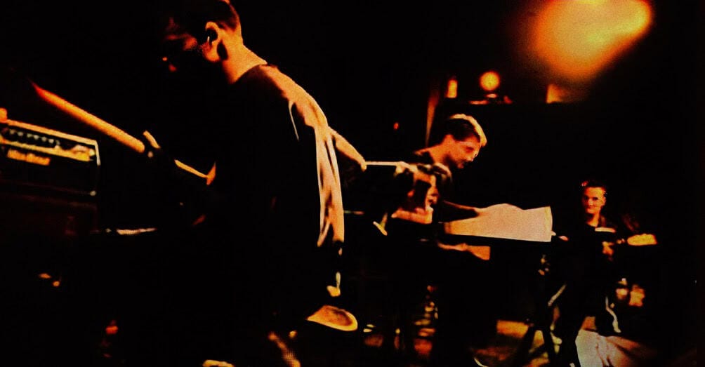 Young musicians playing piano and guitar in a dimly lit music studio, capturing a retro sound archive scene for Past Daily, a comprehensive news, history, and music sound archive.
