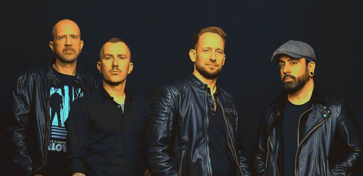 Band members in black leather jackets posing against a dark background for a promotional photo of a music group.