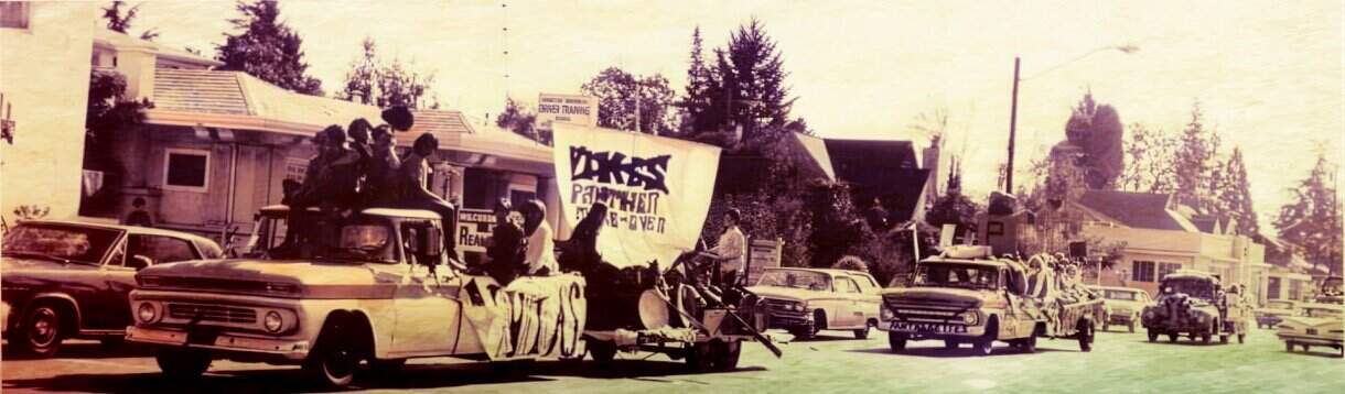 Historic civil rights protest with cars and demonstrators holding banners, capturing a significant moment in American history and social movements.