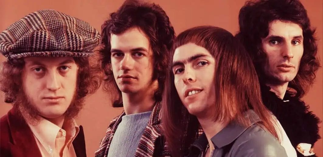 Vintage rock band members, 1970s style, iconic musicians with curly hair, retro clothing, band photo for music history enthusiasts, past daily archive focus.